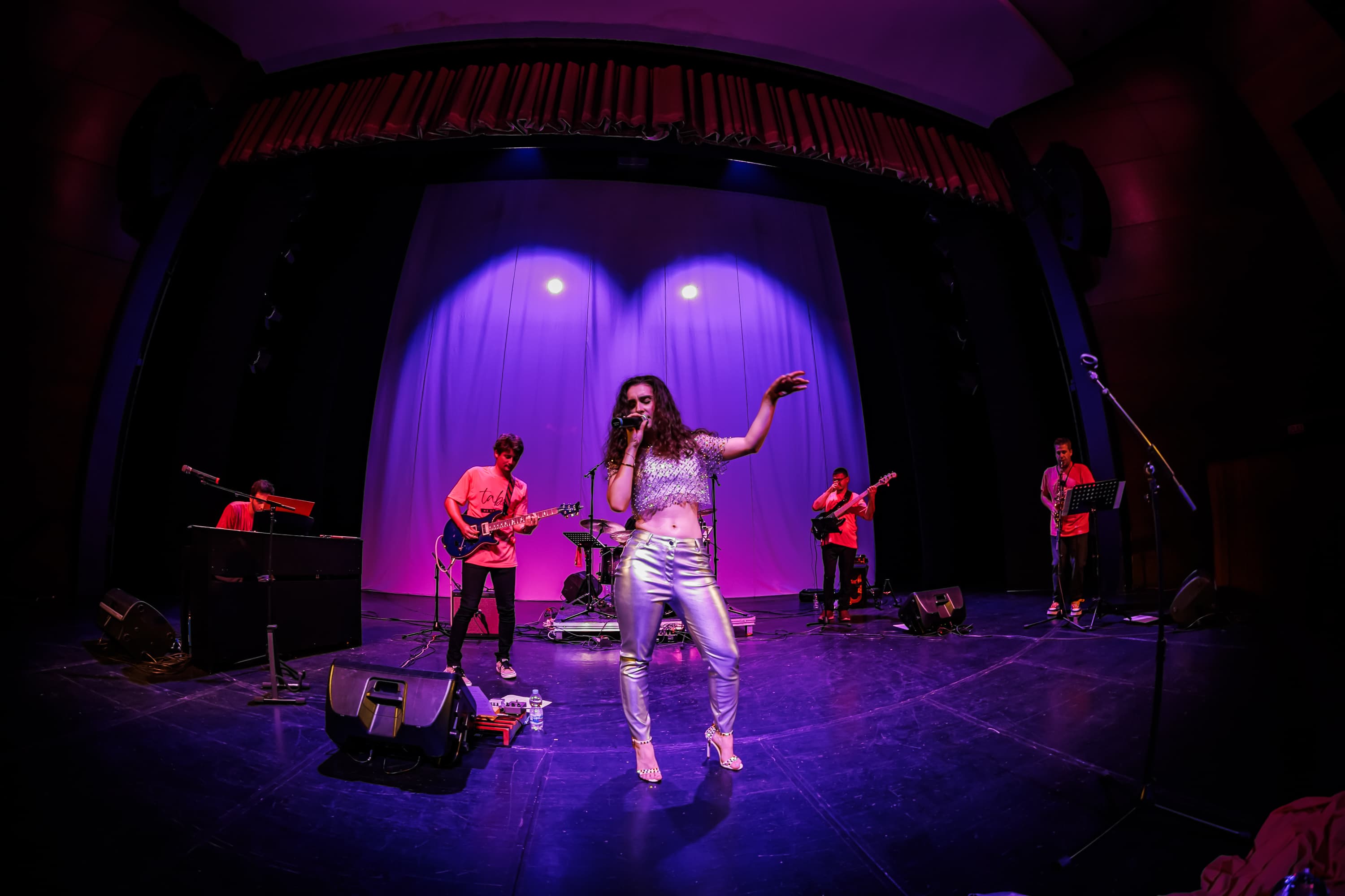 Rebelle singing on stage with her band under purple lights
