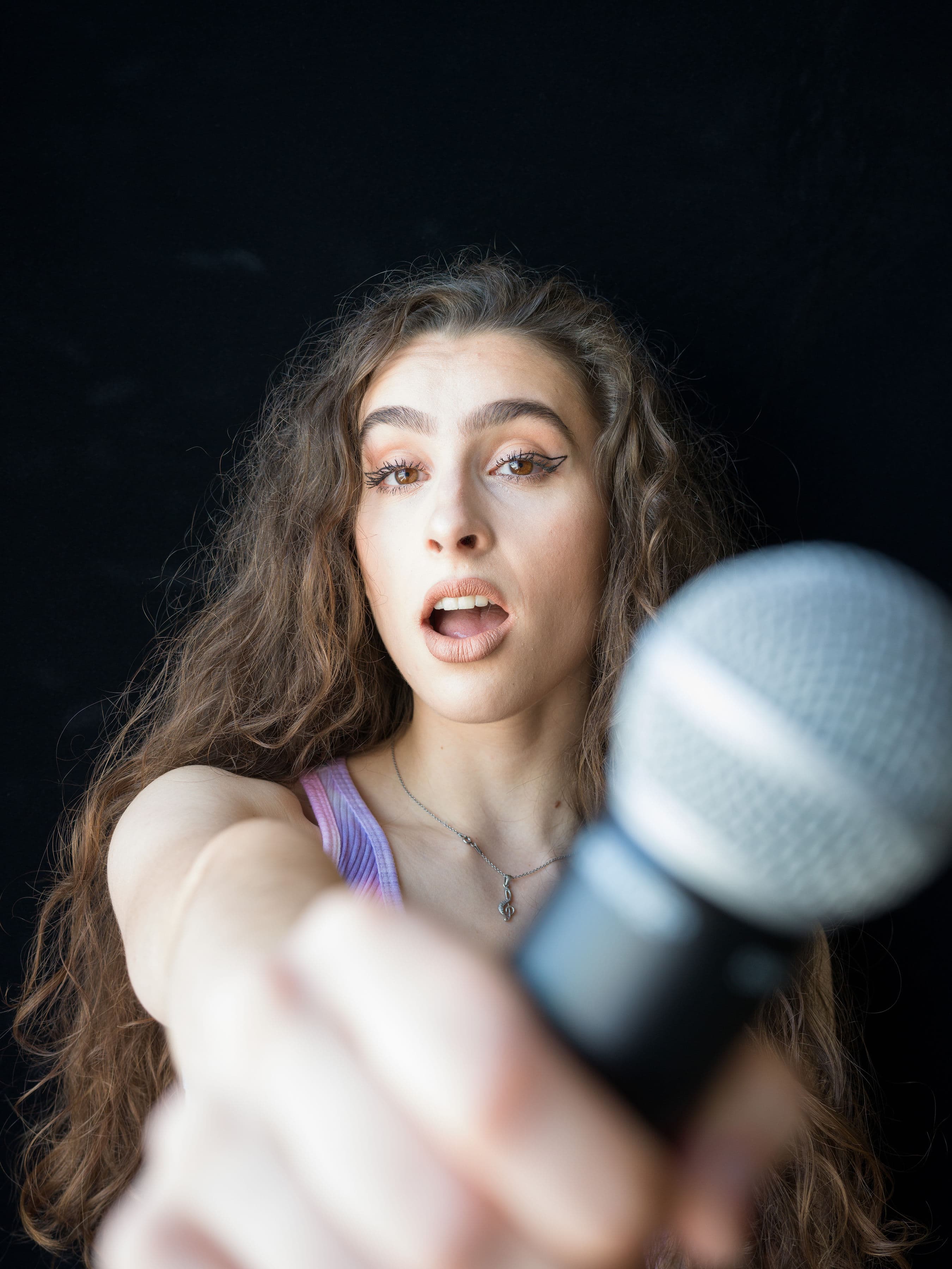 Rebelle holding a microphone toward the camera